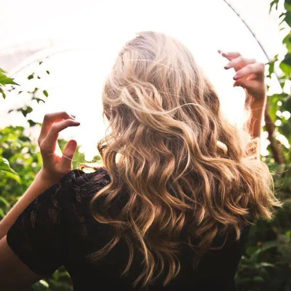 Une femme de dos aux cheveux bouclés couleur chatains.