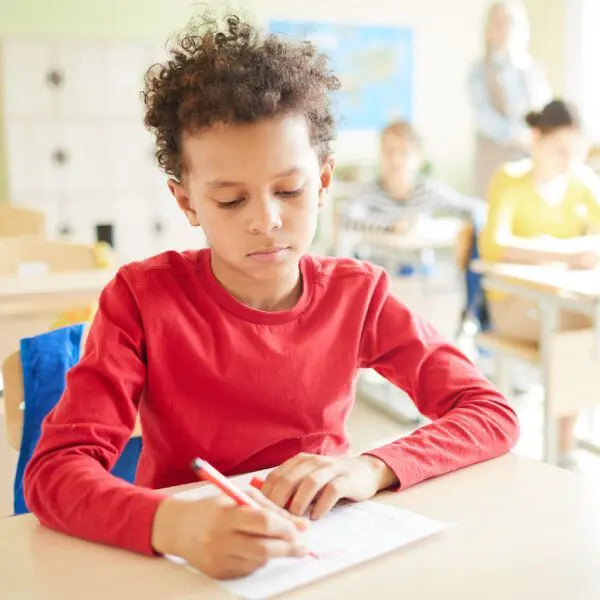 Un enfant à l'école écrit sur un cahier.
