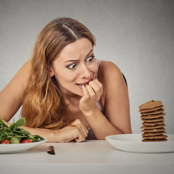 Une femme au régime tentée par une pile de pancakes plutôt que par une salade.