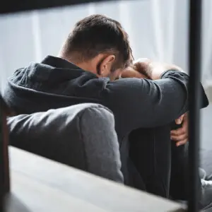 Un homme courbé assis au sol, crise d'angoisse, attaque panique.