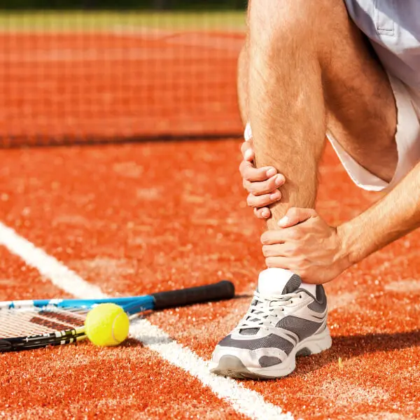 Un joueur de tennis s'agrippe la cheville de douleur.