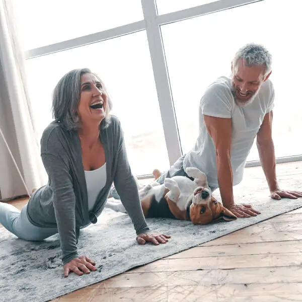 Un couple de seniors s'amusent en pratiquant le yoga avec leur chien.