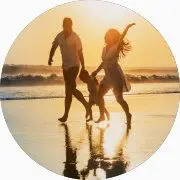 Un couple et leur enfant marchent sur la plage au coucher de soleil.