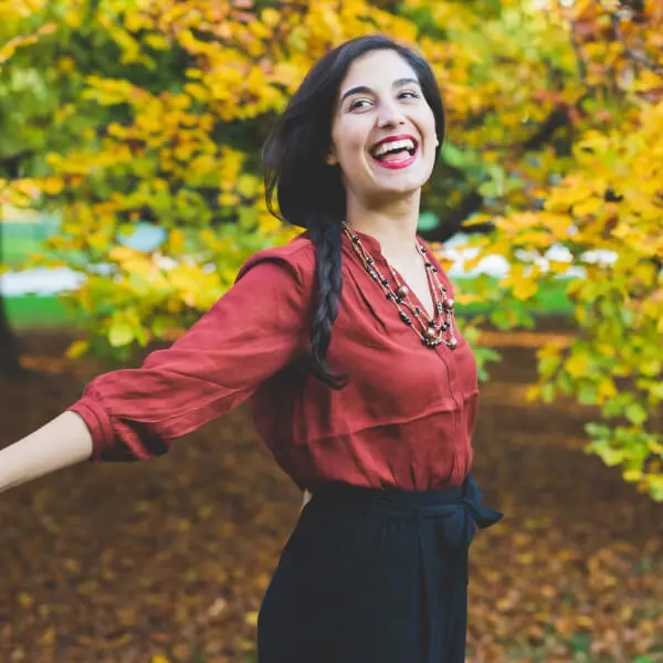 Une jeune femme souriante dans la forêt.