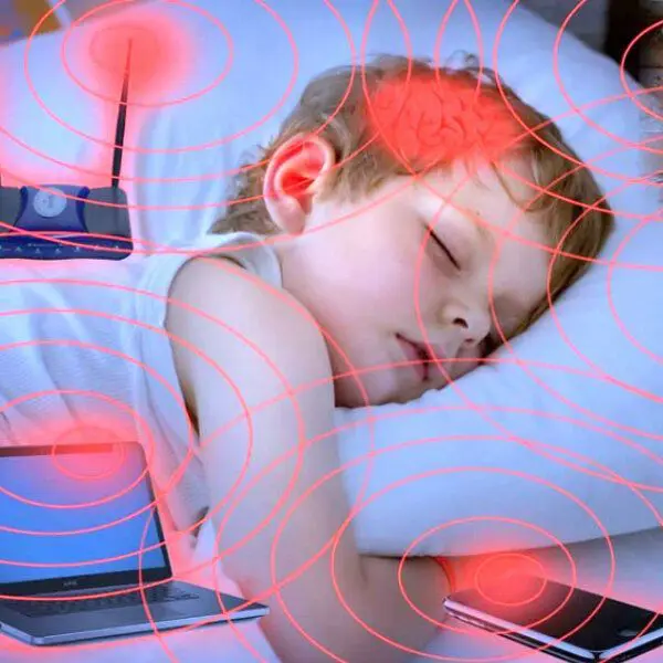 Un enfant endormi, des ondes électromagnétiques sortent d'appareils électroniques autour de lui.