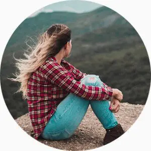Une femme assise au sol regarde l'horizon au loin.