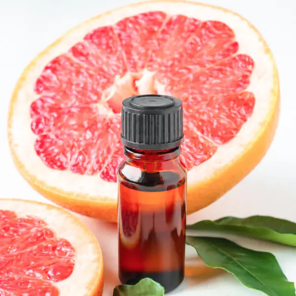 Extrait de pépins de pamplemousse bio dans un flacon devant un pamplemousse coupé en deux.