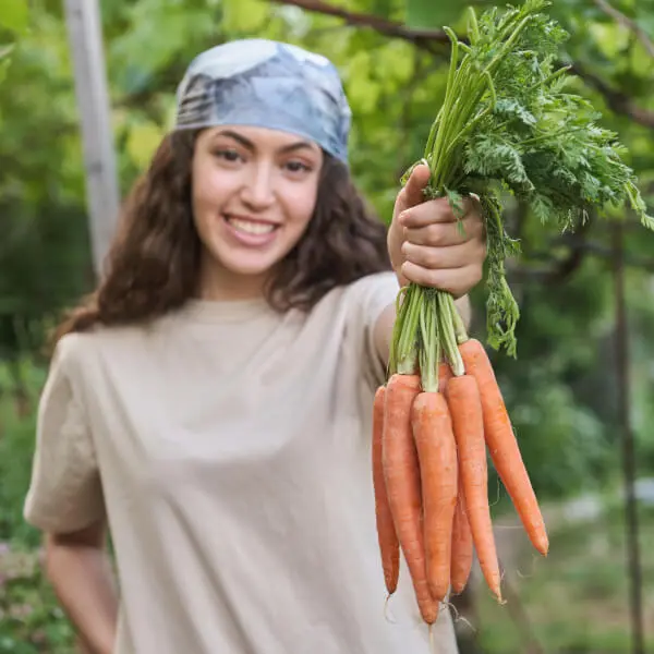 Une jeune fermière brandit des carottes.