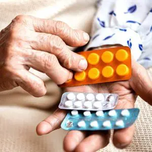 Mains d'une personne âgée touchée par l'arthrite et l'arthrose avec des médicaments anti-inflammatoires.