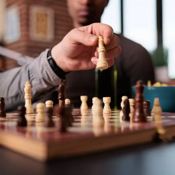 Gros plan sur un jeu d'échec, une main tient une pièce.