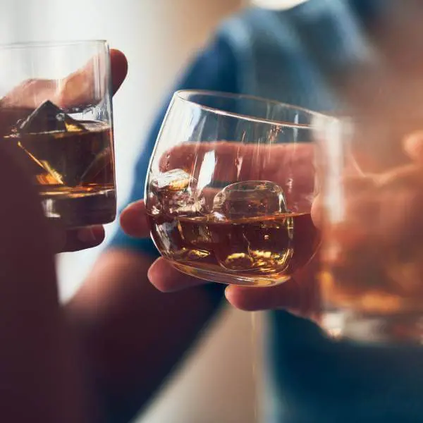Gros plan sur deux personnes qui trinquent avec de l'alcool.