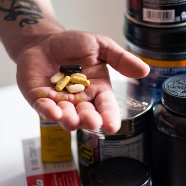 Une main de bodybuilder avec des compléments alimentaires.
