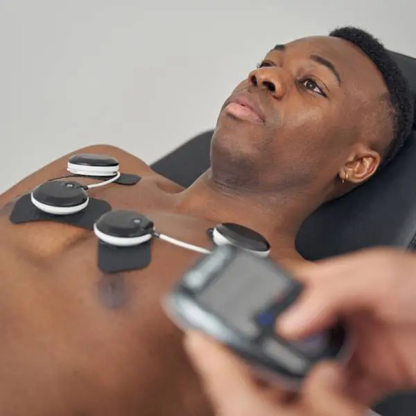 Des électrodes sur le torse d'un jeune homme pour l'électrostimulation musculaire.