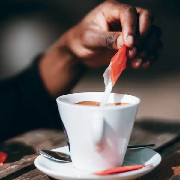 Quelqu'un ajoute du sucre raffiné dans un café.