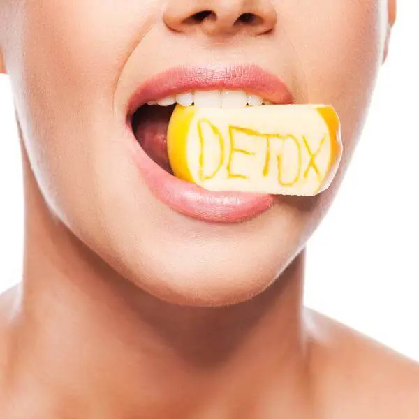 Une femme croque un citron sur lequel est écrit le mot "détox".