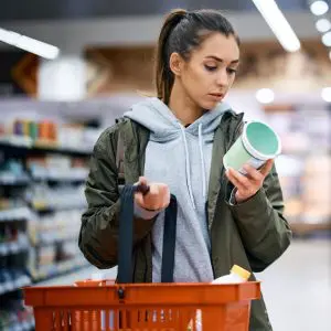 Une jeune femme dans un supermarché étudie l'étiquette d'un yaourt pour les intestins.