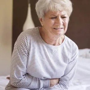 Une dame se tient le ventre de douleur se demandant si son estomac est malade.