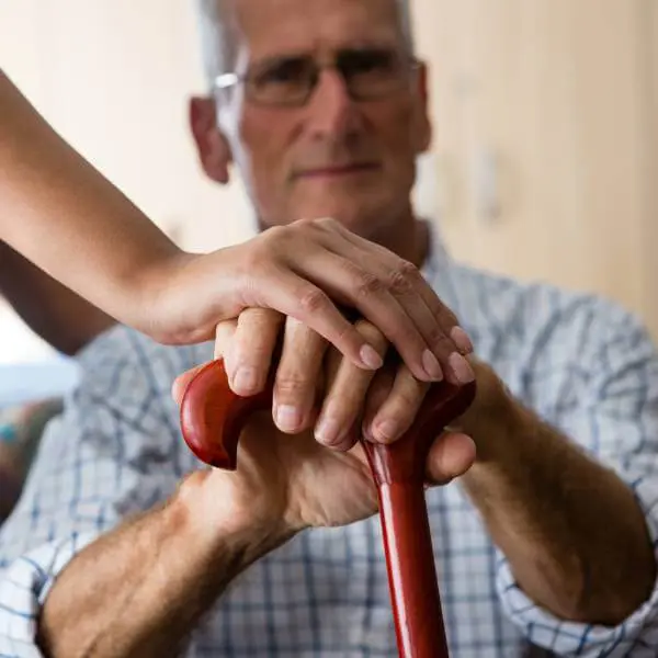Un homme âgé touché par la maladie de Parkinson se tient sur une canne.