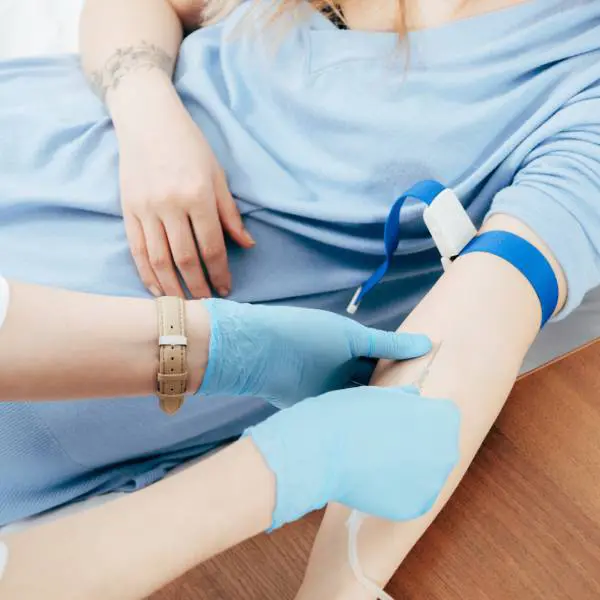 Une infirmière injecte une seringue dans le bras d'un patient pour pratiquer une aphérèse ou lavage du sang.