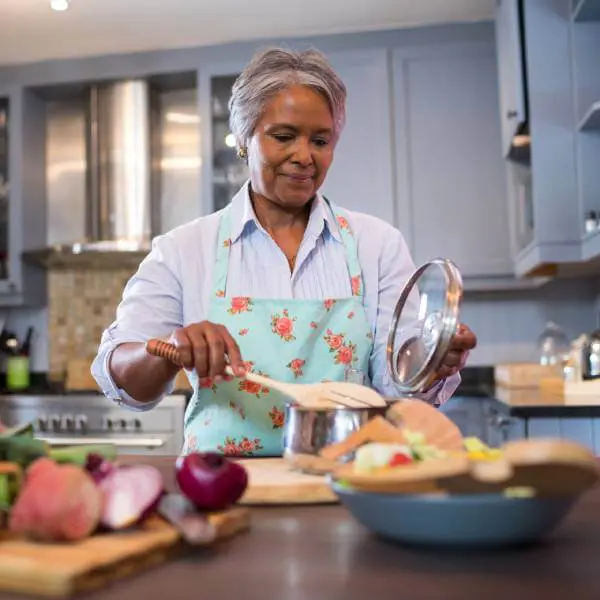 Une dame cuisine des aliments sains.