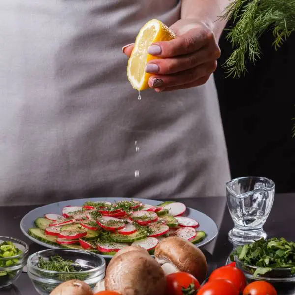 Une femme presse un citron au-dessus d'une assiette préparée avec des aliments pour nettoyer le sang.