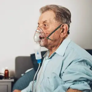 Un homme âgé porte un masque de supplémentation en oxygénation pour pallier à un manque d'oxygène dans le sang.