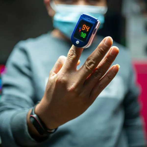Un médecin démontre comment utiliser un oxymètre sur son doigt.