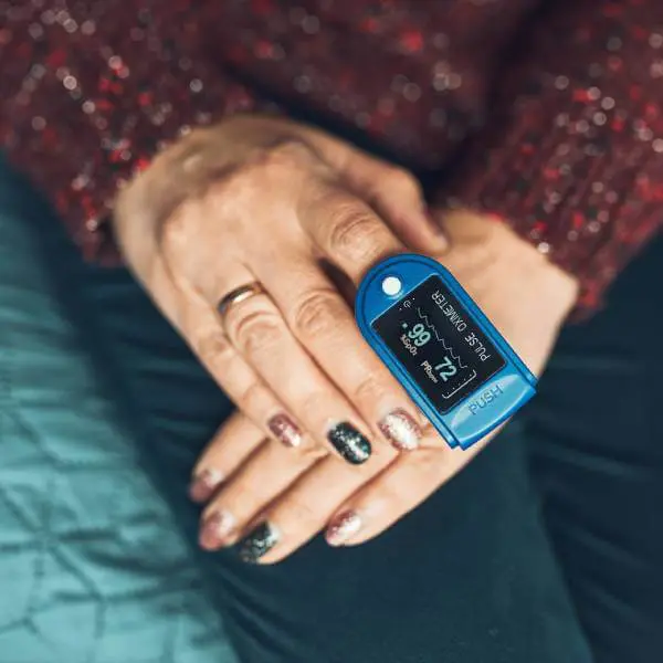 Gros plan sur deux mains et un oxymètre de pouls.