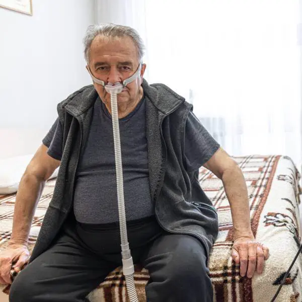 Un homme âgé touché par le COVID long avec un masque respiratoire en oxygène.