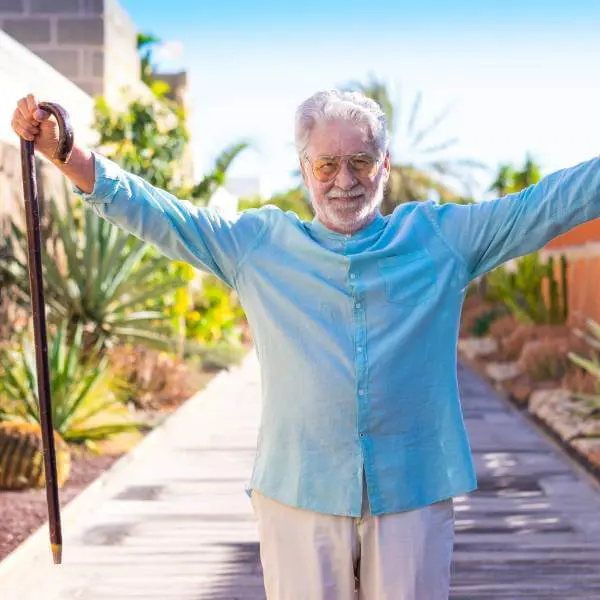 Un senior en pleine forme lève les bras sous un ciel ensoleillée.