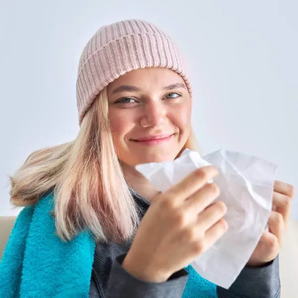 Une jeune femme enrhumée mais souriante.